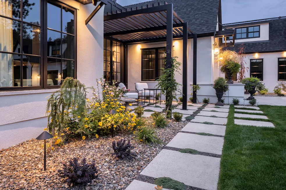 Landscape lighting in a walkway and softscapes with a house in the background