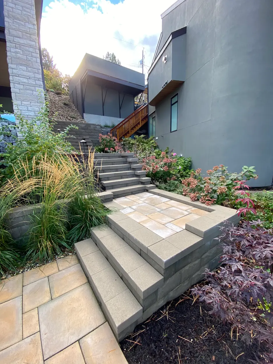Spiral staircase with grassses and shrubs in the background with vibrant paver stones